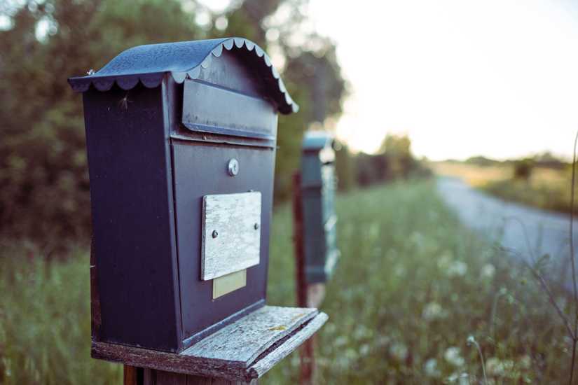 A blue mailbox sitting lonely in a grass field